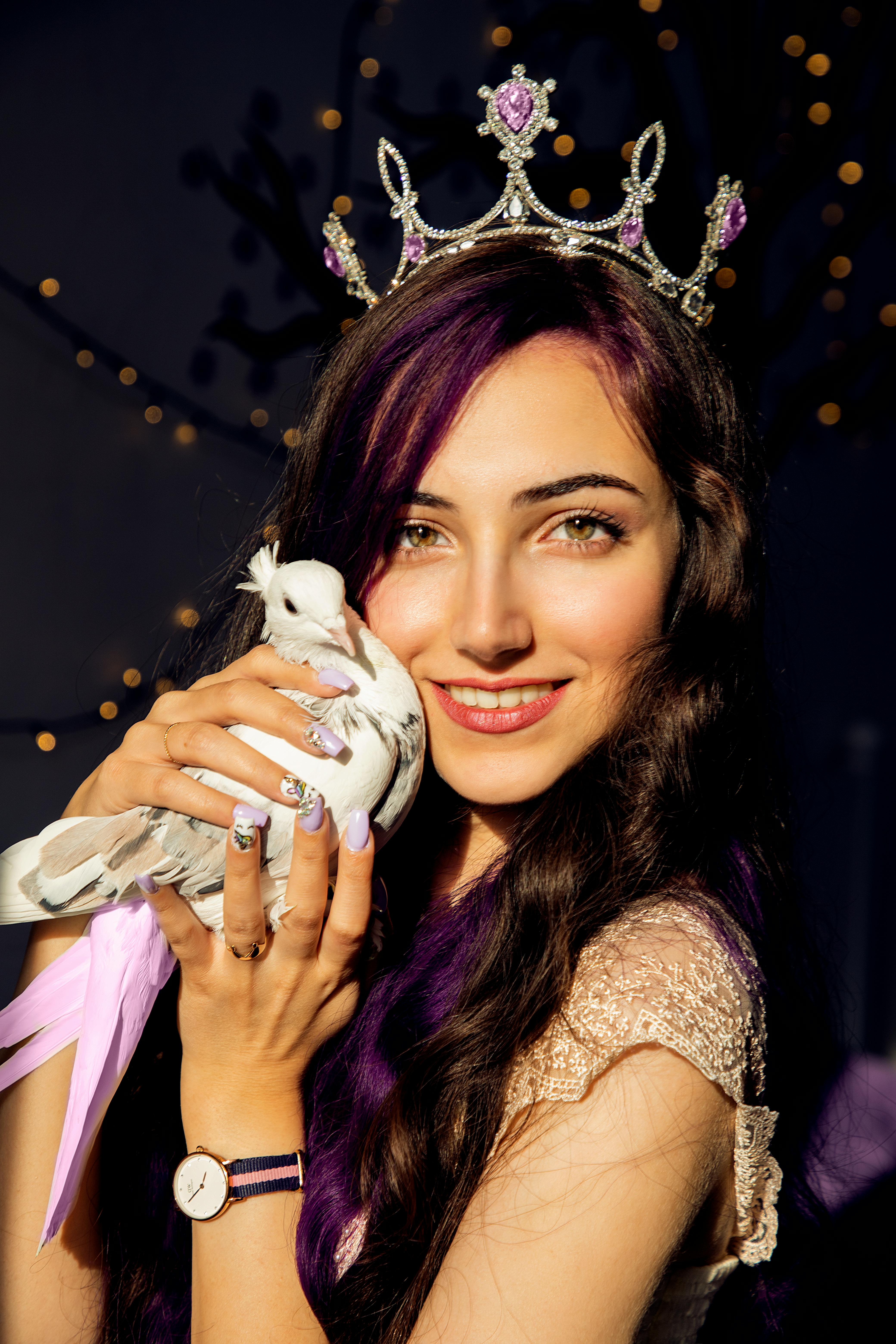 close up photo of a woman wearing a crown holding a white dove