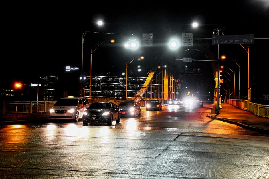 Cars on Ft Duquesne Bridge at night with illuminated city backdrop. Vibrant urban night scene.