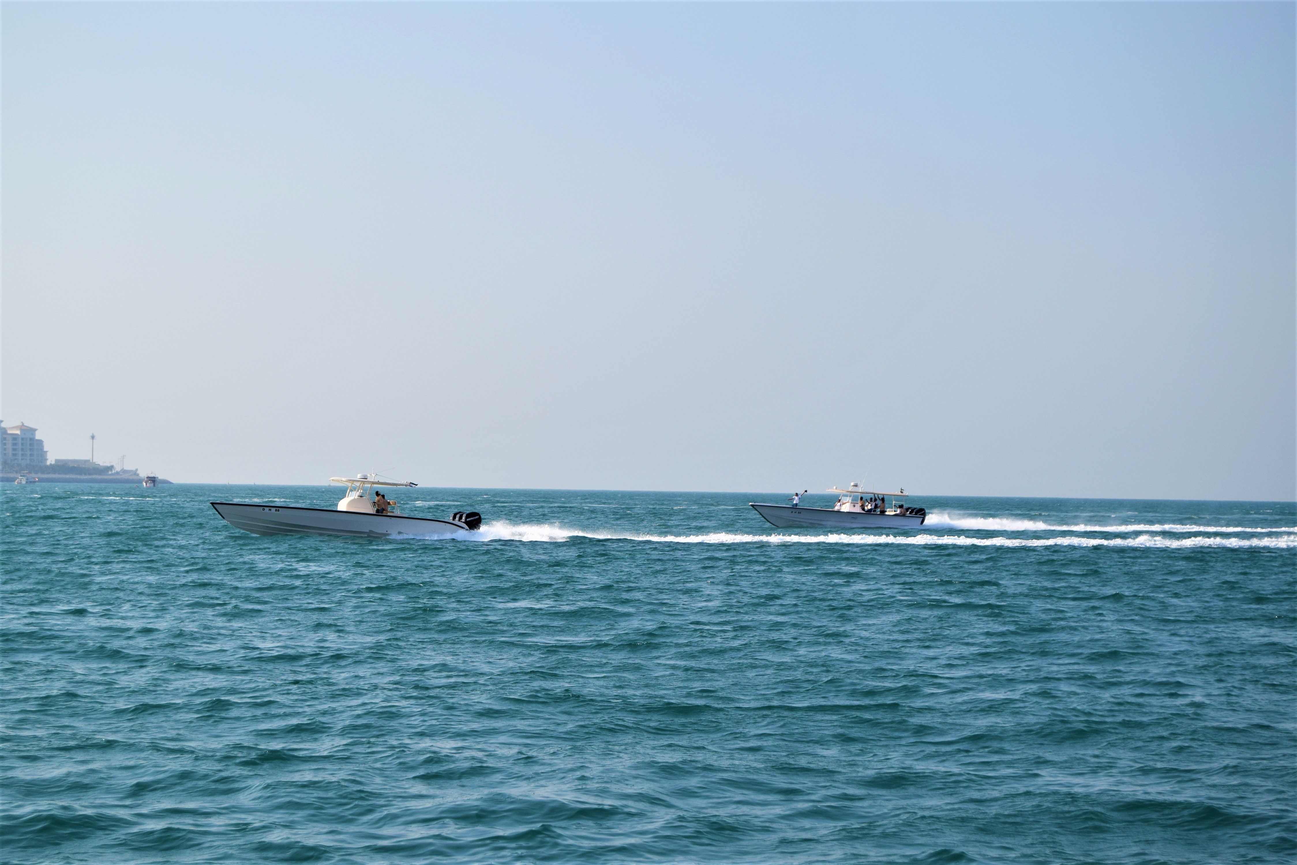 Two speedboats racing on the turquoise waters off Dubai's coast under a clear blue sky.