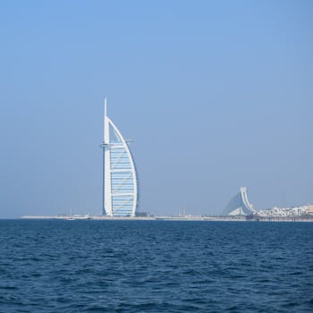 Iconic Burj Al Arab hotel stands tall by the ocean under a clear blue sky in Dubai.