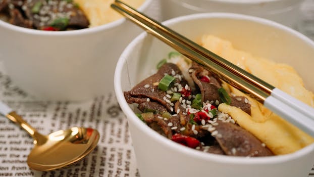 A delicious Japanese beef rice bowl garnished with sesame seeds and chopsticks, captured up close.