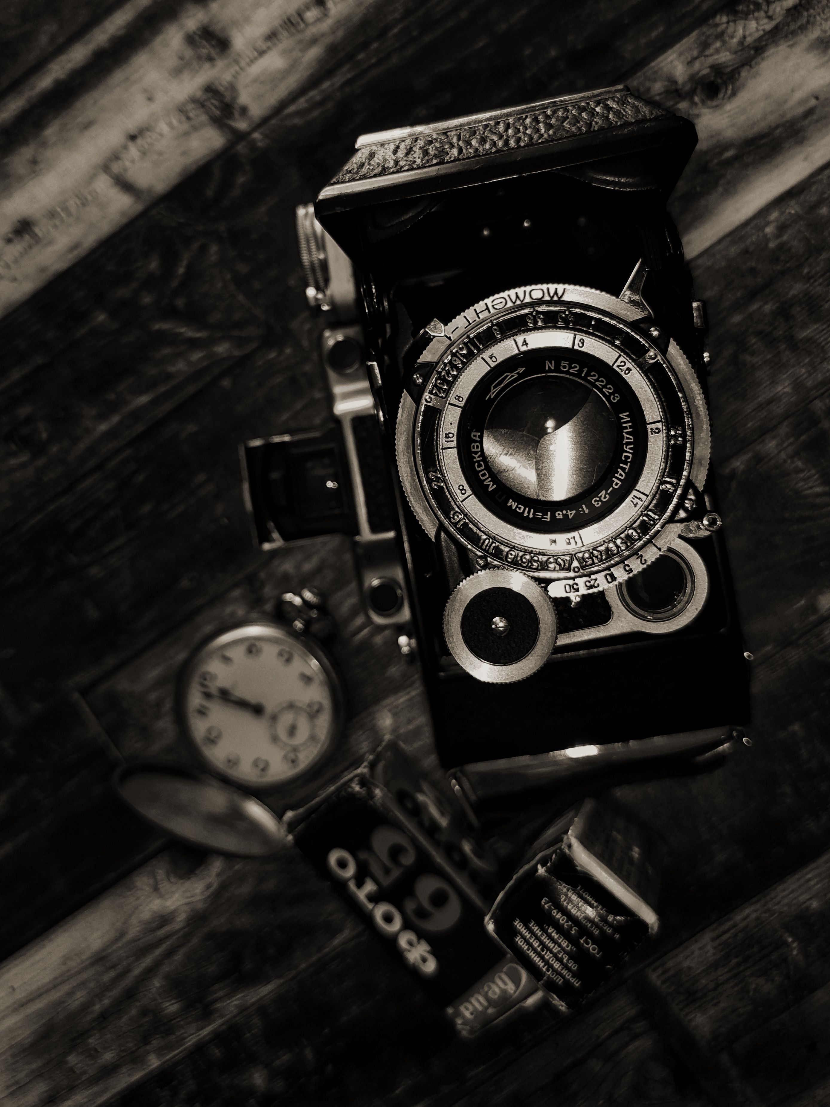 A flat lay of a classic vintage camera with retro accessories in a moody setting.