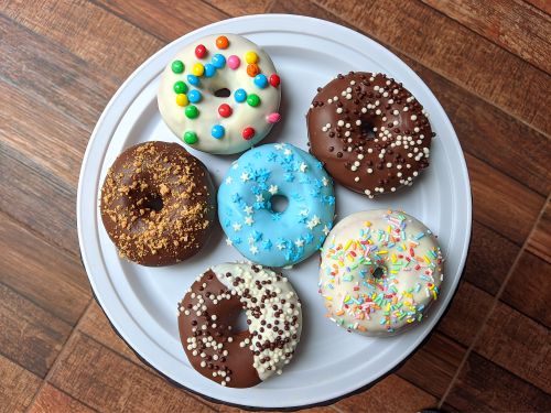 Free A vibrant assortment of decorated donuts placed on a white plate, perfect for any dessert lover. Stock Photo