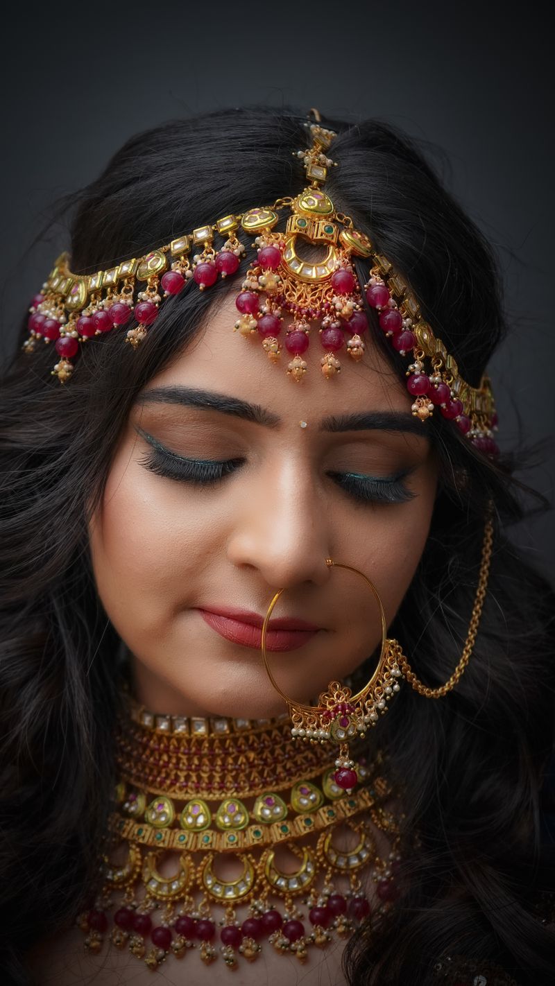 Gold maang tikka with hanging chains and emerald accents
