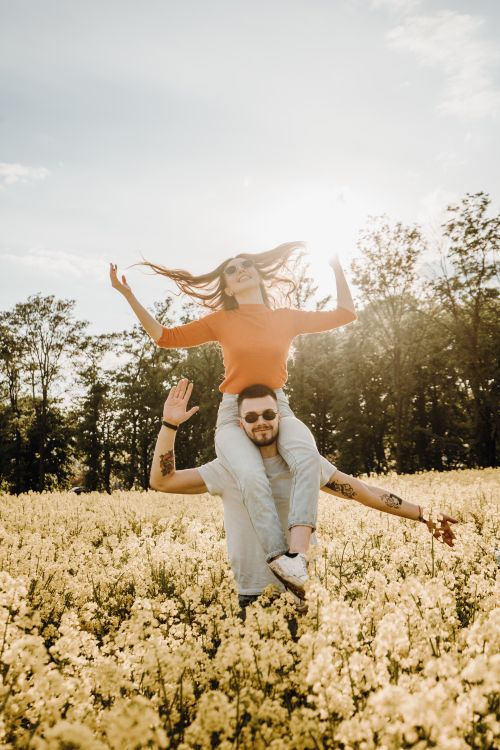 Free Carefree couple having fun and piggybacking in a sunny floral field. Stock Photo