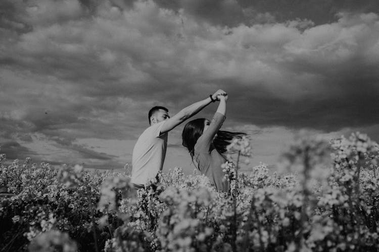 Grayscale Photo Of A Couple Dancing On A Field Of Yellow Flowers