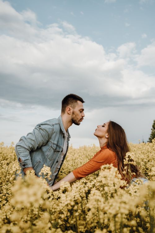 Free A couple enjoying a romantic moment in a blooming meadow under a blue sky. Stock Photo