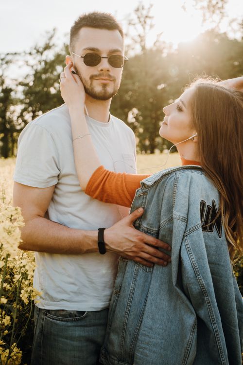 Free Young couple embracing in a sunlit field, showcasing love and affection in a summery outdoor setting. Stock Photo