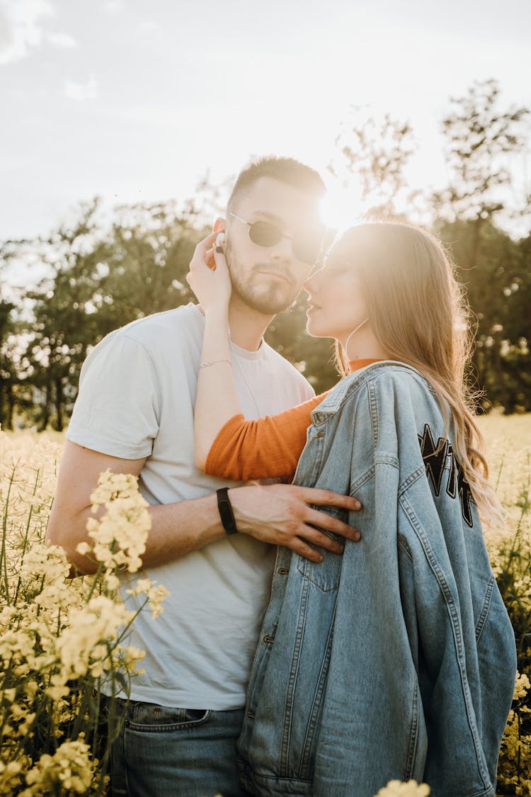 Couple Standing Together With Woman Putting Headphone Into Mans Ear 