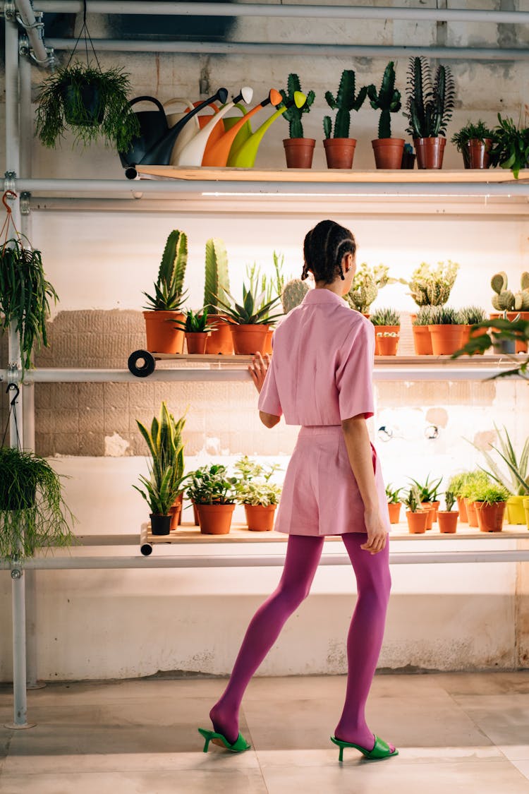 Woman In Purple Stockings And Green Heels Standing In Front Of Potted Plants 