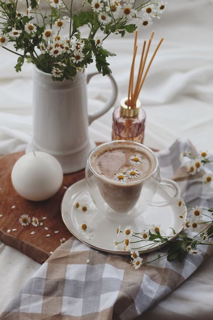Warm chamomile latte with floral decor and diffuser on a cozy setting.