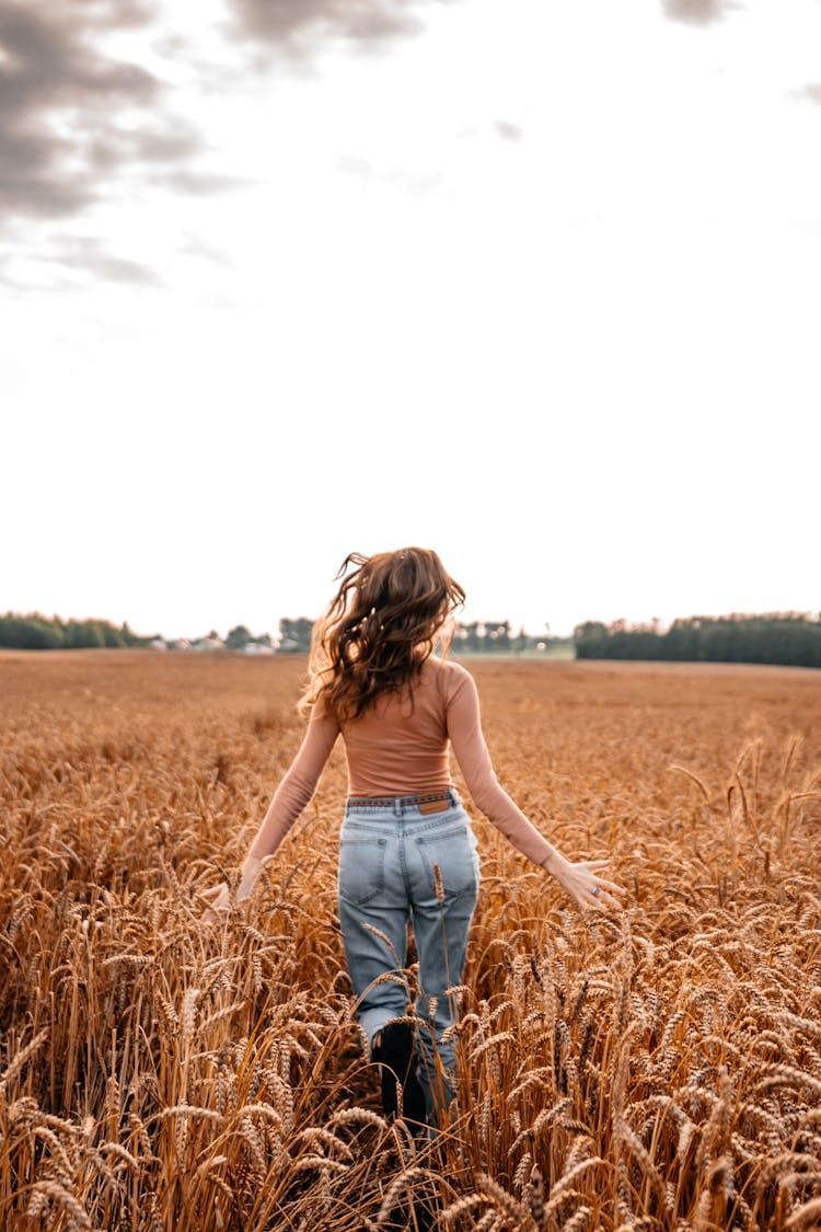 A Woman In Denim Jeans Running On The Field