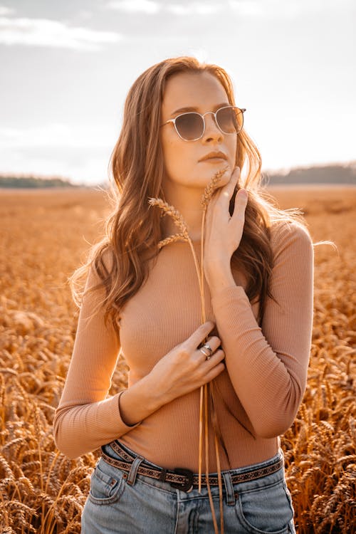 Selective Focus Photo of a Woman Wearing Sunglasses Holding Wheats