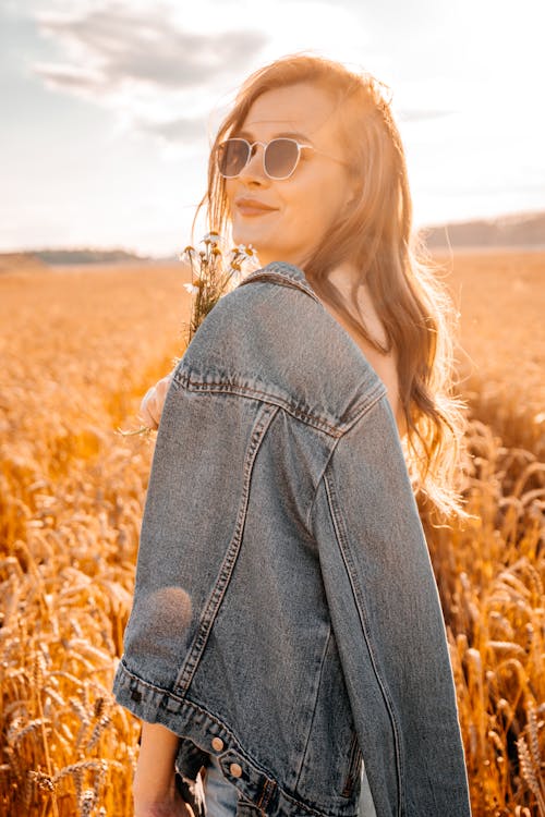 Woman Holding his Denim Jacket While in a Wheat Field