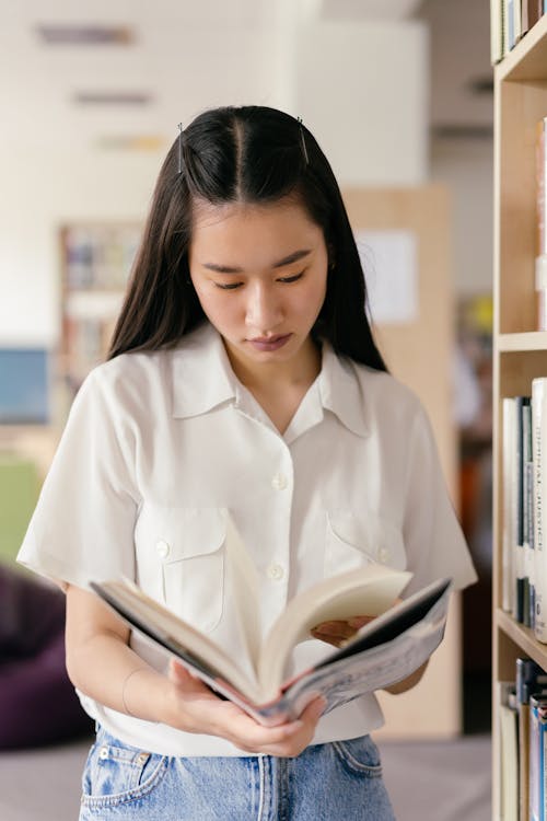 Free Woman in a Library Reading a Book Stock Photo