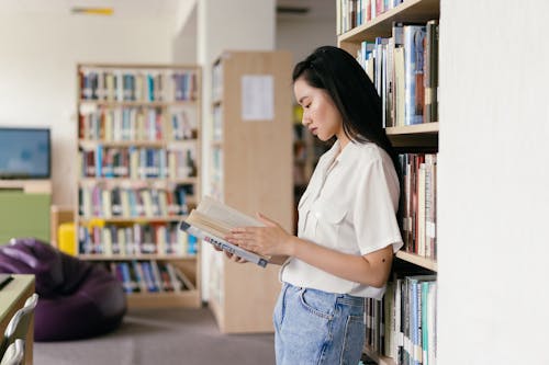 Студентка читает книгу в библиотеке
