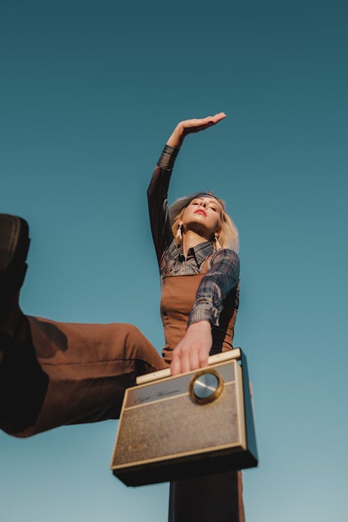 A Low Angle Shot of a Woman in Brown Jumper Holding a Radio