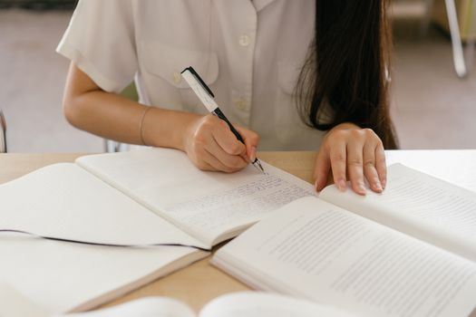 Woman writing notes in a notebook, focusing on study. Hands visible close-up.