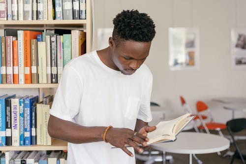 A Man in White Shirt Reading a Book