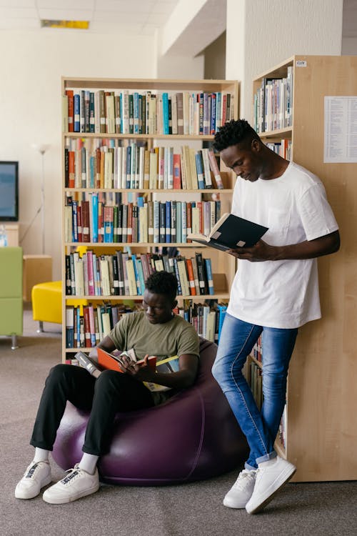 Estudantes Do Sexo Masculino Lendo Livro Na Biblioteca