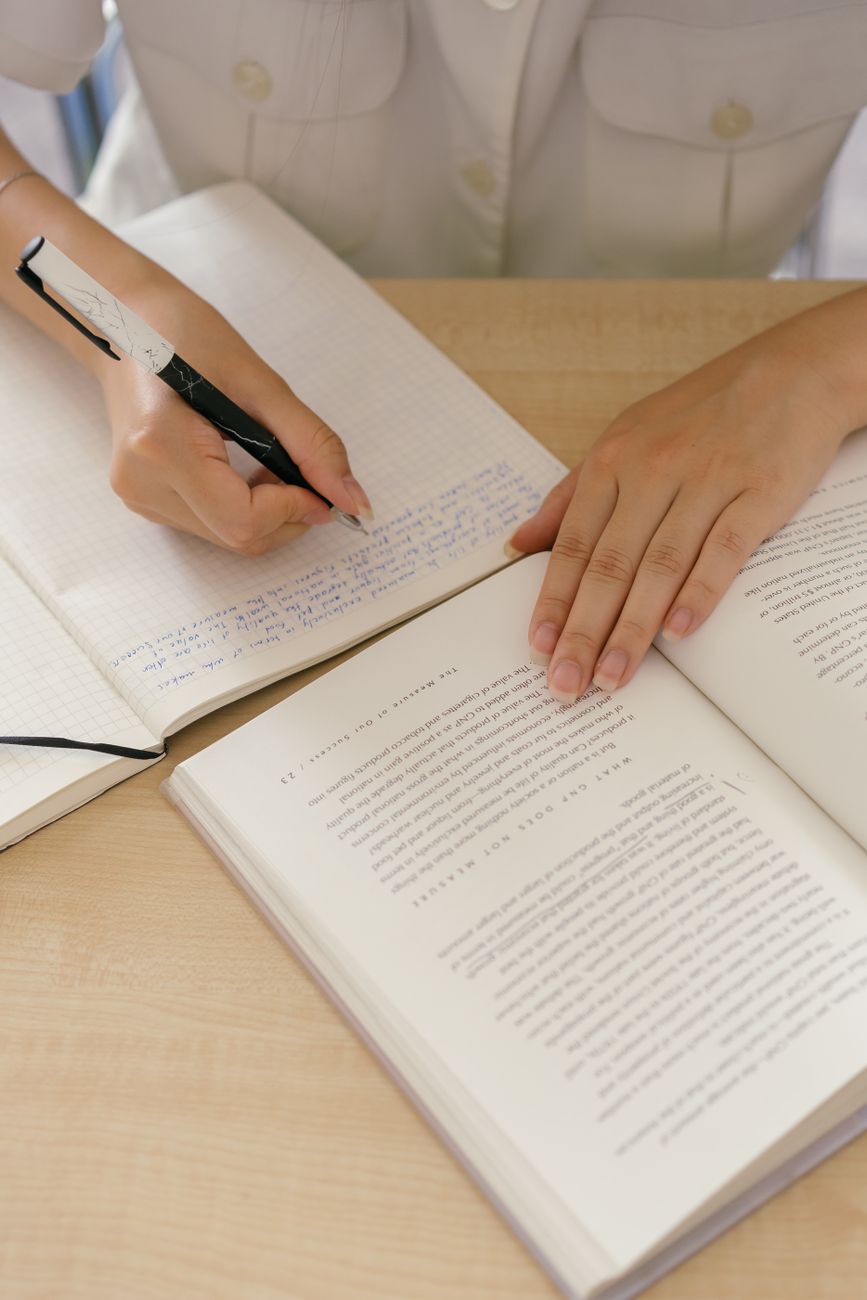 Reader taking notes beside an open nonfiction book