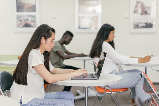 Students focused on learning in a contemporary university setting with laptops and notebooks.