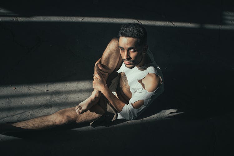 Man In Torn Shirt Posing In Dark