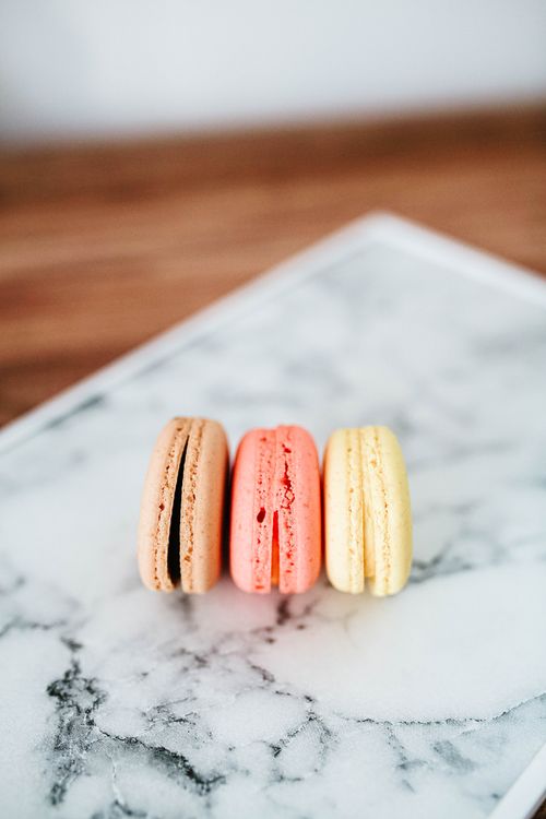 Free Three colorful French macarons on a marble surface, perfect for dessert themes. Stock Photo