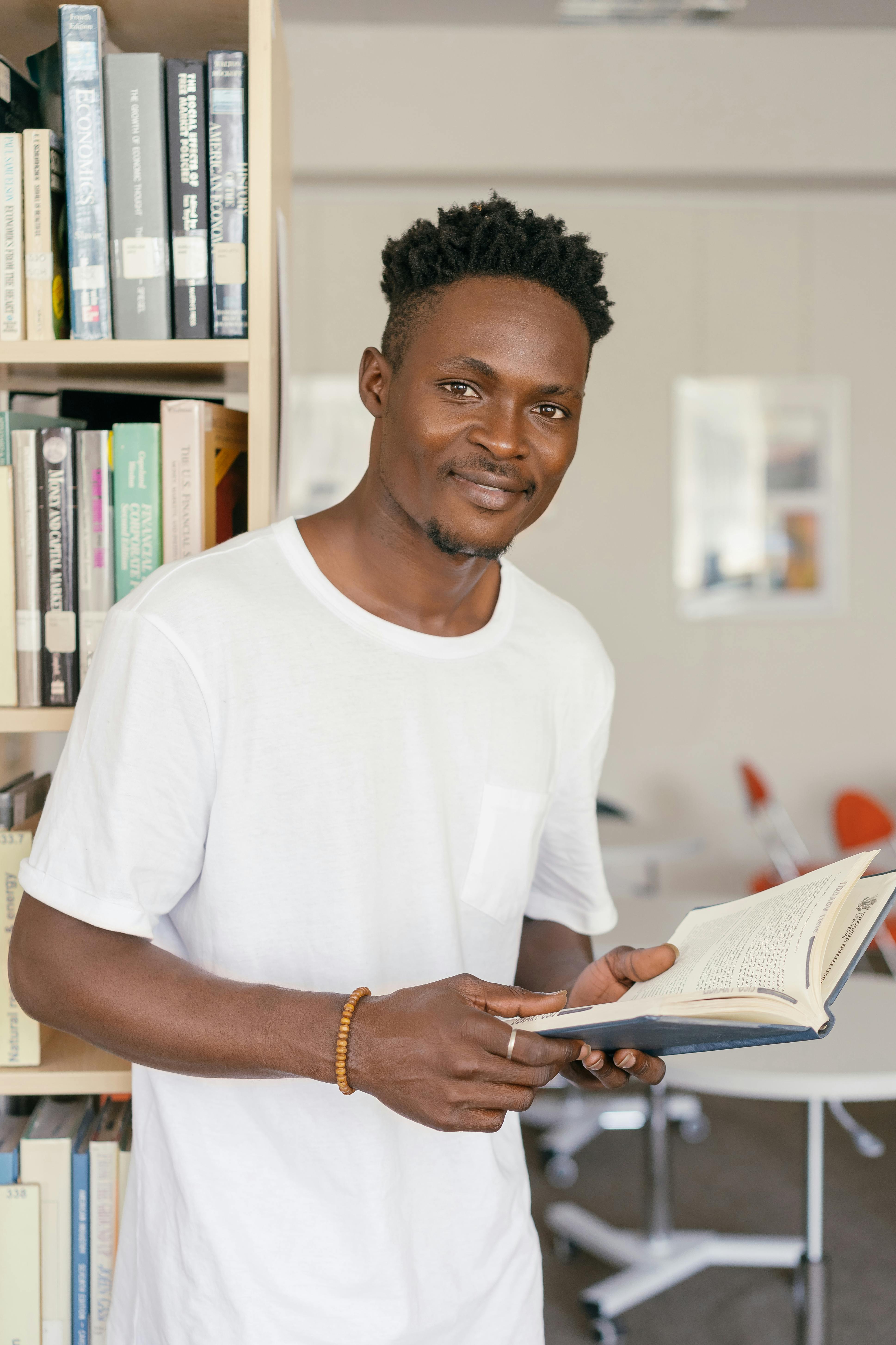 man in a white crew neck shirt holding an open book