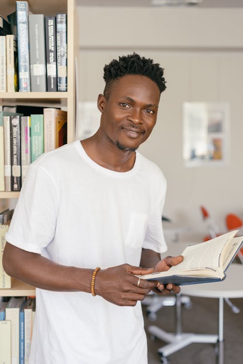 Free Man in a White Crew Neck Shirt Holding an Open Book Stock Photo