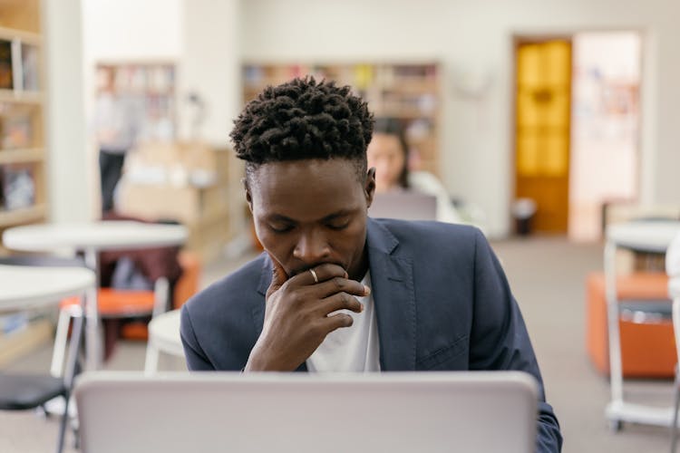 Man In A Gray Blazer In Front Of A Computer In A Classroom