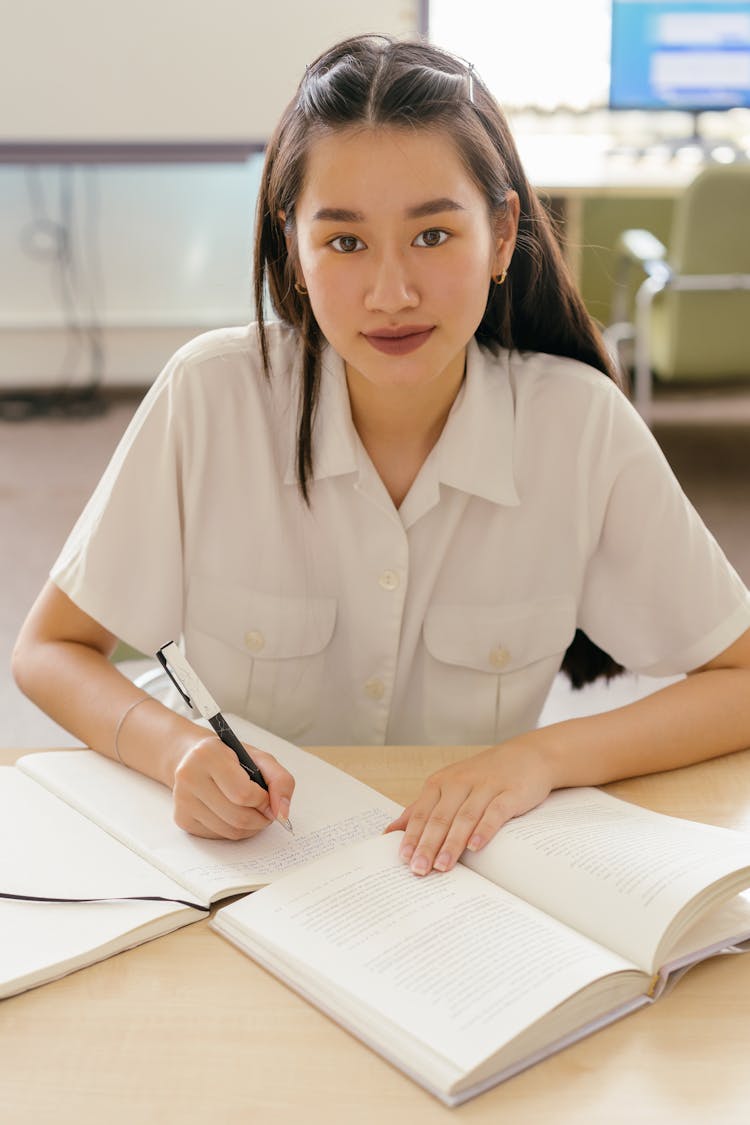 A Woman In White Polo Writing On Notebook