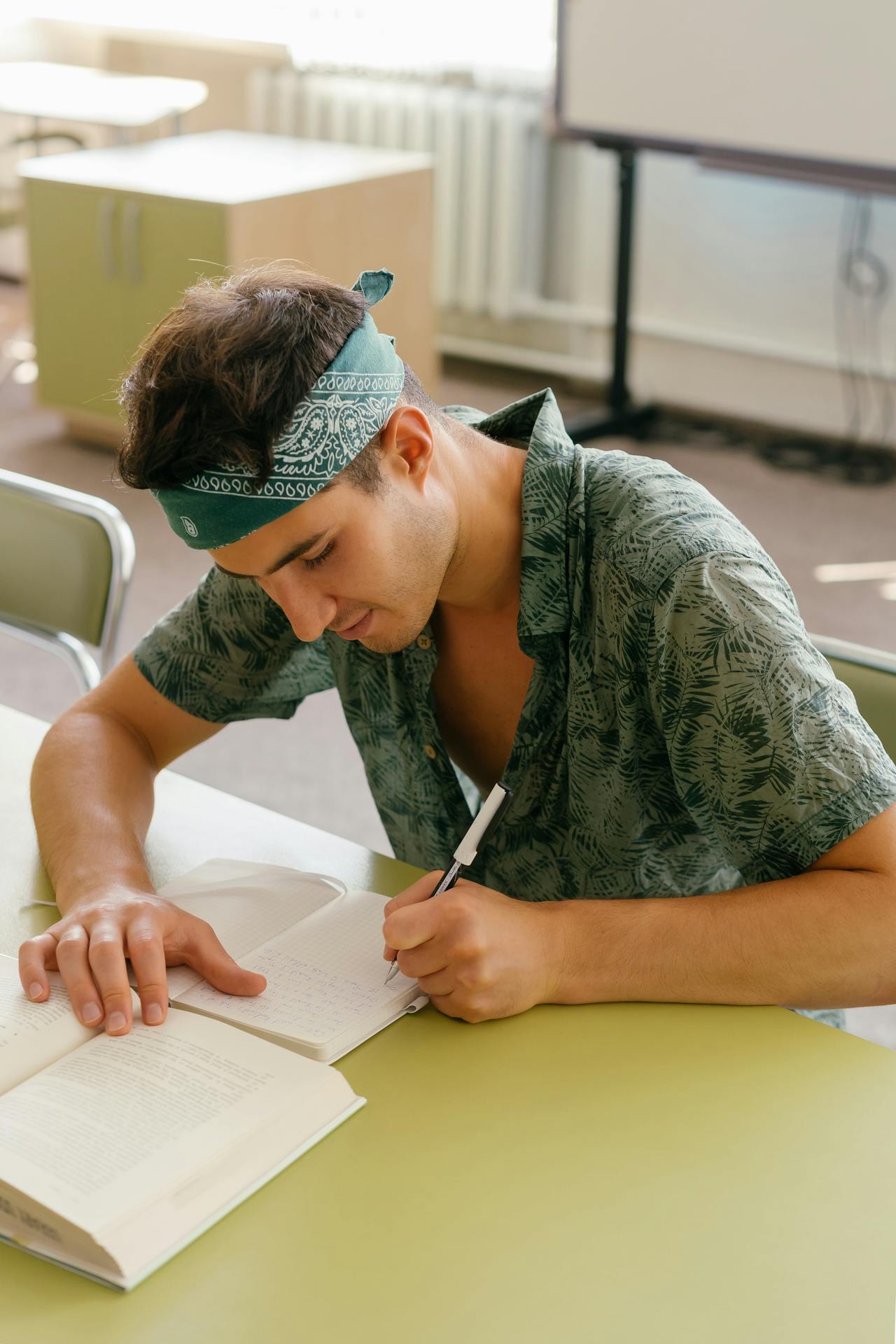 Primo piano di lettore che segna una checklist accanto a libro aperto