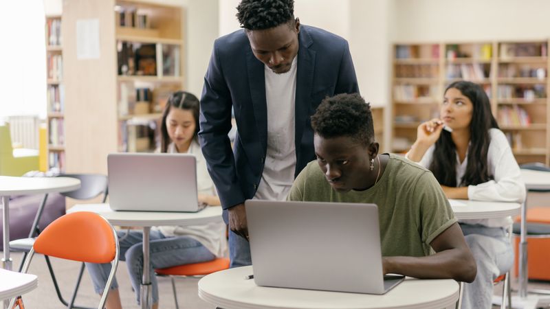 Teacher reviewing a student's work in a bright classroom