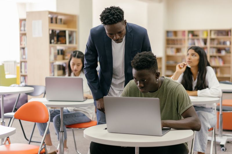 students working together over laptops in a library — photograph by Mikhail Nilov on Pexels