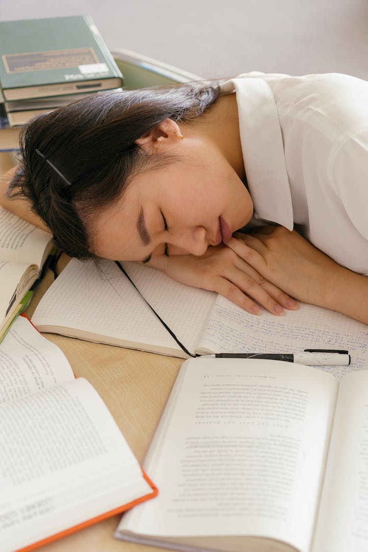 A Woman Sleeping On The Desk With A Notebook