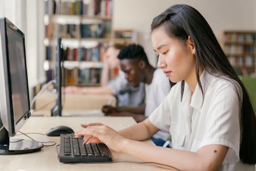 Students using computers in a library, focused on academic research and learning.