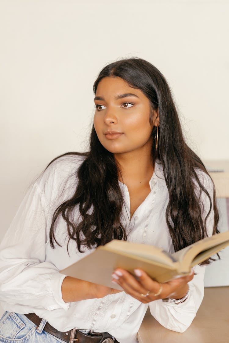 A Pretty Girl In White Long Sleeve Shirt Holding A Book