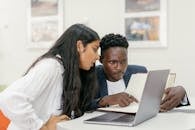 A Professor and a Student Sitting at a Desk with a Computer and a Book