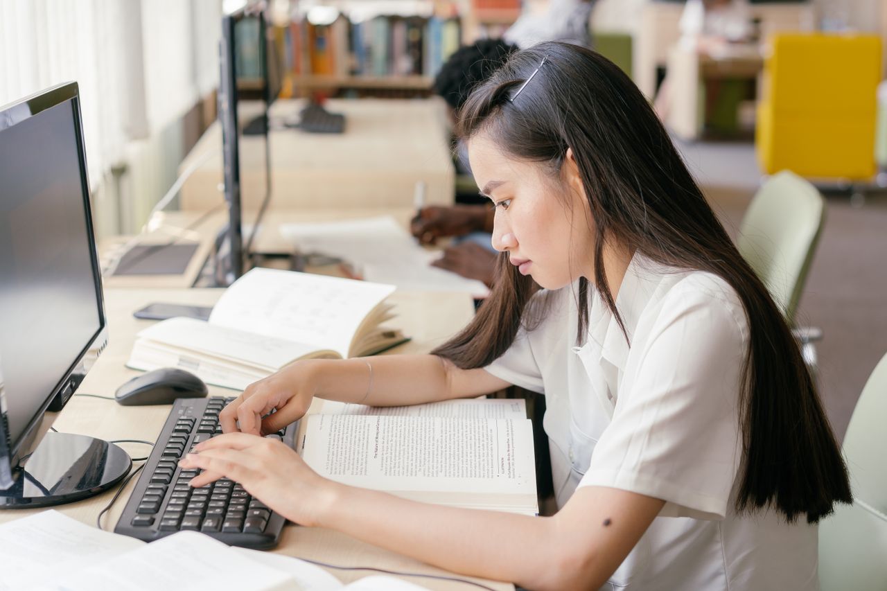 tech-learning-zone-classroom Student studying with books and a computer in a school library