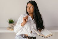 Woman in White Dress Shirt and Blue Denim Jeans Sitting on White Chair