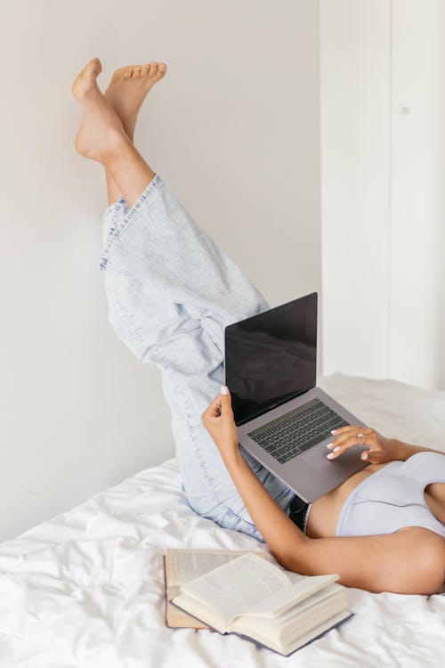 Free A Woman Lying on the Bed while Using Her Laptop Stock Photo