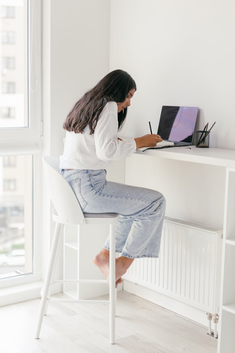 A Woman Sitting On A Stool While Studying