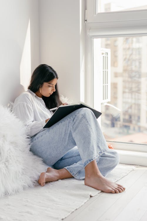 Free A Woman Sitting on the Floor While Studying Stock Photo