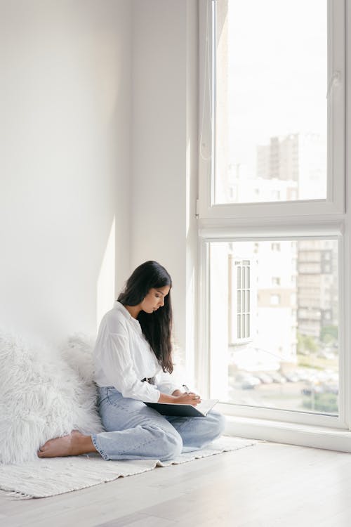 A Woman Sitting on the Floor While Studying