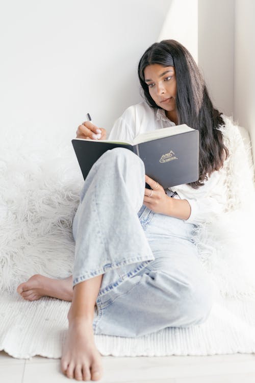 Free A Woman Sitting on the Floor While Studying Stock Photo