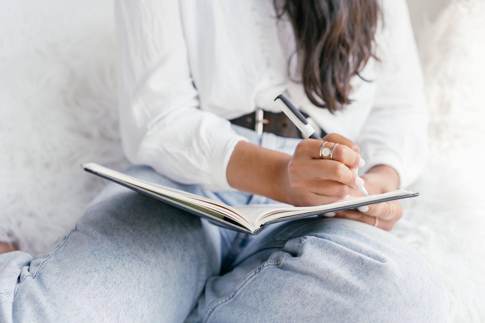 A Person in White Long Sleeve Shirt Writing on a Notebook