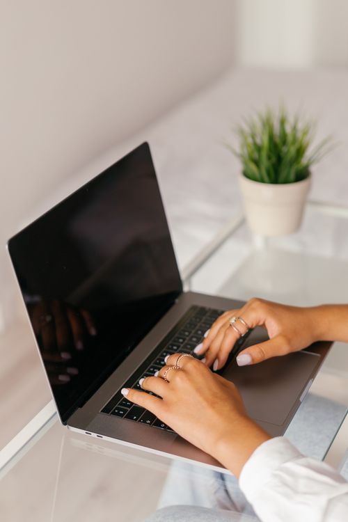 Free Close-up of woman's hands typing on a laptop at a glass table. Modern and minimalistic setting. Stock Photo