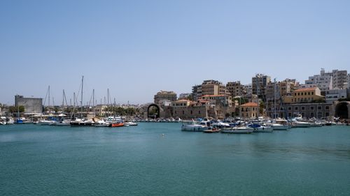 Free Beautiful view of Heraklion harbor with sailboats and cityscape under a blue sky. Stock Photo