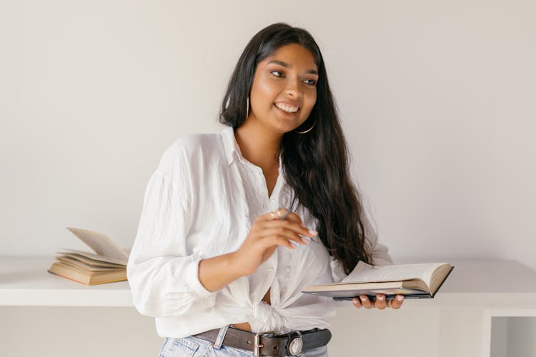 Female Student Smiling While Holding A Book